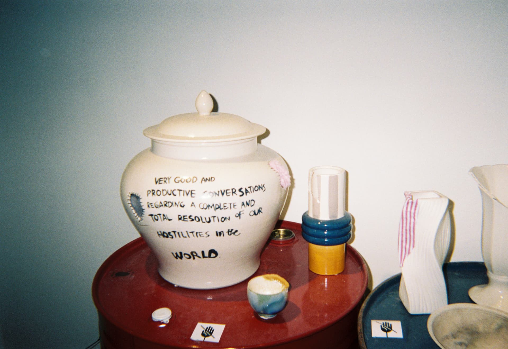 A ceramic jar with handwritten text on a red table