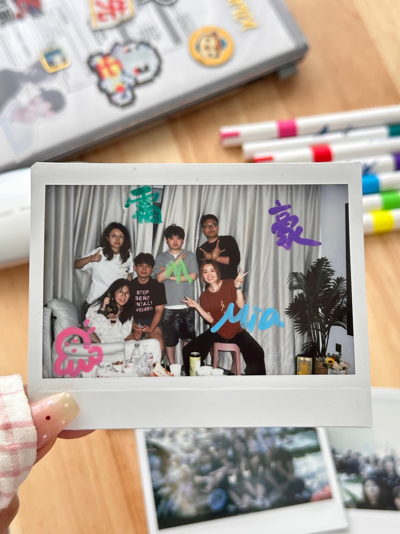 A polaroid photo held above a table with markers