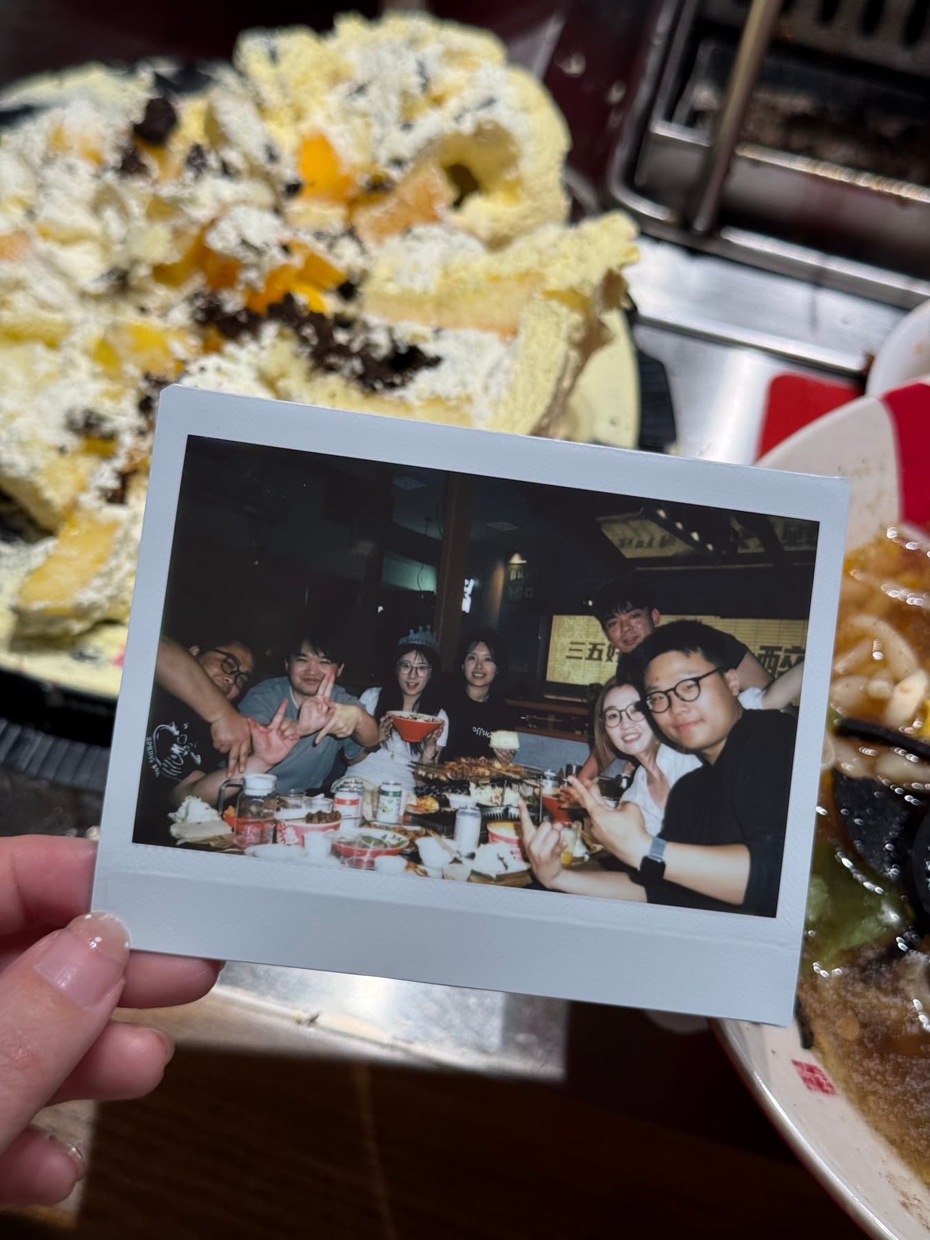 A polaroid photo held above a dinner table